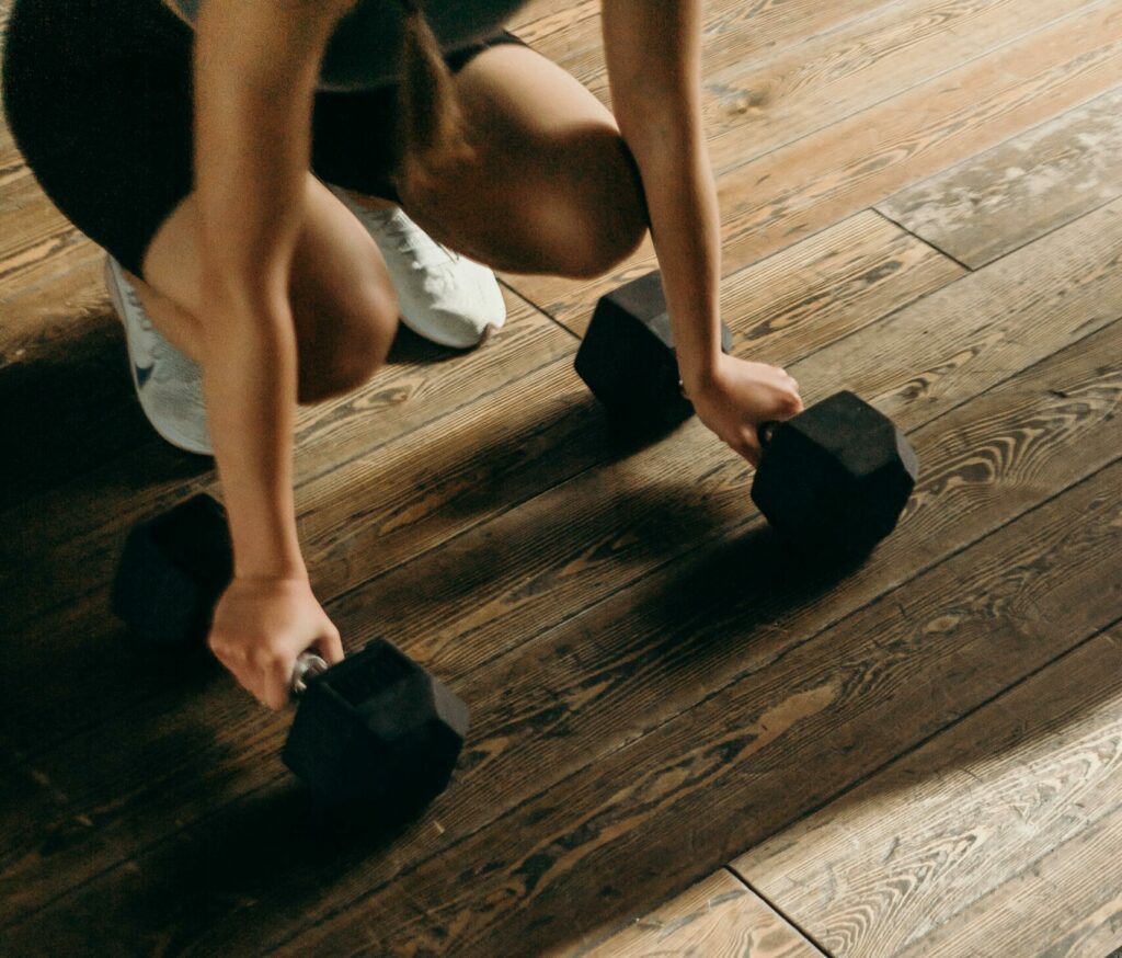 Femme en short dans un studio prète à soulever deux haltères de 6 kilos chacune