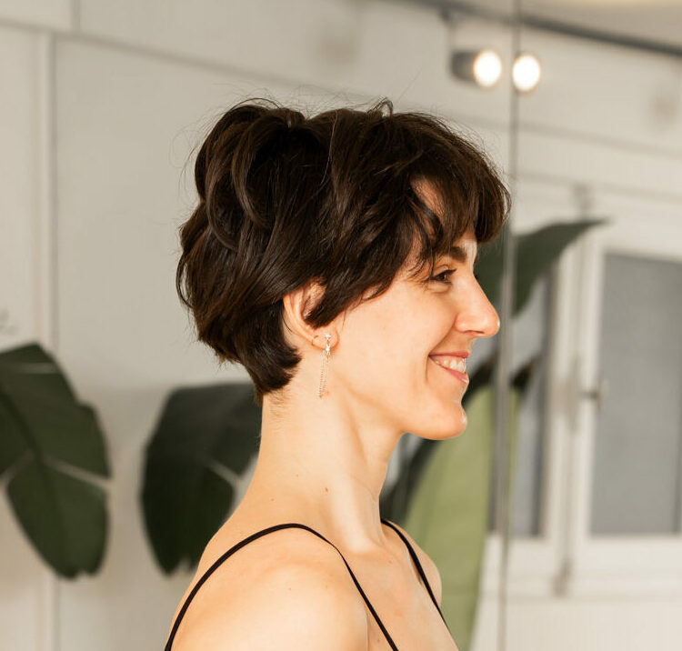 Profil d'une femme au cheveux court souriante dans un studio de Pilates